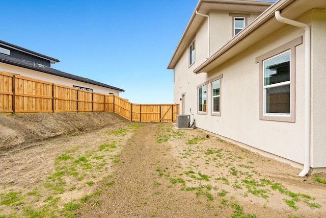 view of yard with central air condition unit and fence