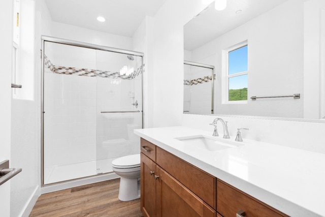 bathroom with recessed lighting, toilet, vanity, a shower stall, and wood finished floors