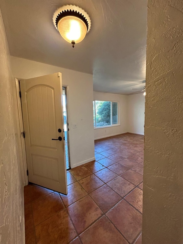 tiled entryway with ceiling fan, baseboards, and a textured wall