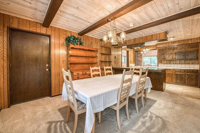 dining room with wooden ceiling, light colored carpet, beamed ceiling, and wooden walls