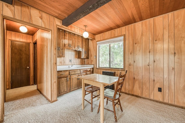 kitchen with light countertops, light carpet, wood walls, wooden ceiling, and beamed ceiling