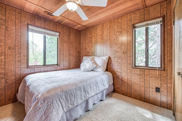 carpeted bedroom featuring visible vents, wooden ceiling, multiple windows, and wooden walls