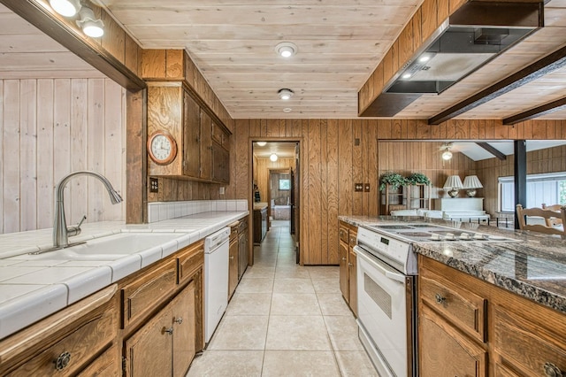 kitchen with light tile patterned floors, white appliances, brown cabinetry, and a sink