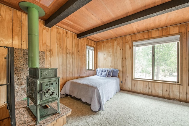 carpeted bedroom featuring wooden walls, baseboards, wooden ceiling, beamed ceiling, and a wood stove