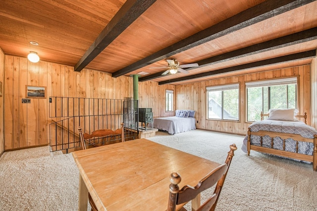 bedroom featuring wooden ceiling, wood walls, carpet flooring, beamed ceiling, and a wood stove