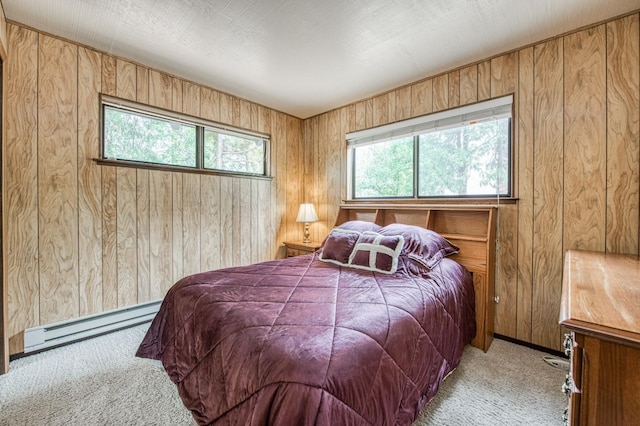 bedroom featuring multiple windows, baseboard heating, carpet, and wooden walls