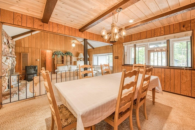 carpeted dining room with wooden ceiling, vaulted ceiling with beams, wooden walls, and an inviting chandelier