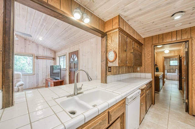 kitchen with a sink, wooden ceiling, tile counters, and dishwasher