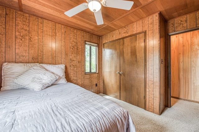 carpeted bedroom with wooden ceiling, ceiling fan, wooden walls, and a closet