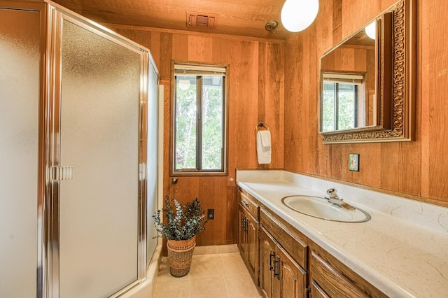 full bathroom featuring wooden walls, vanity, visible vents, a shower stall, and tile patterned floors