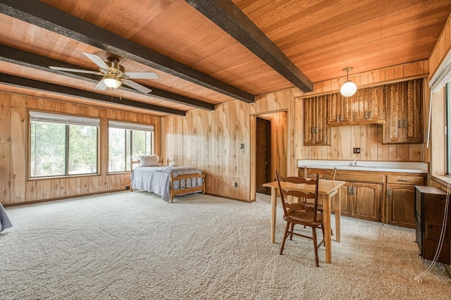 bedroom with wood ceiling, beam ceiling, light carpet, and wood walls