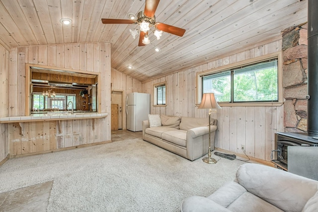 living area featuring lofted ceiling, wooden ceiling, a wood stove, and light colored carpet