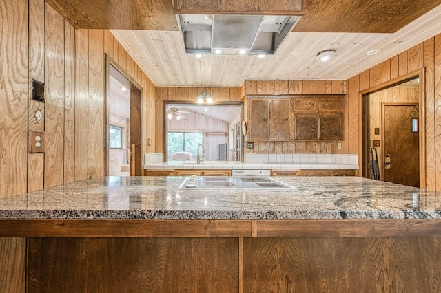 kitchen with brown cabinetry, white electric cooktop, a sink, wooden walls, and wooden ceiling