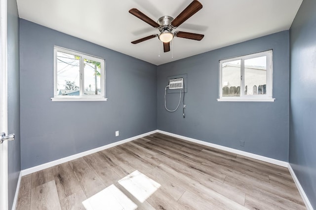 unfurnished room featuring ceiling fan, an AC wall unit, baseboards, and wood finished floors