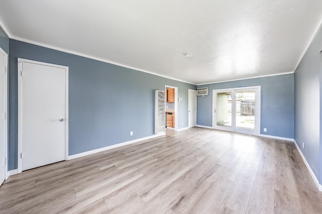 empty room featuring light wood-style flooring, crown molding, and baseboards