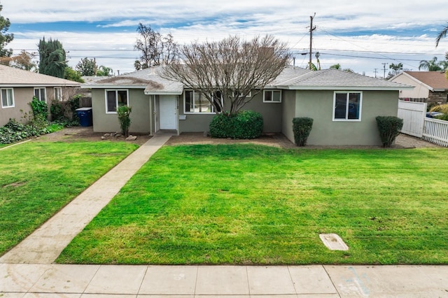 single story home featuring stucco siding, roof with shingles, a front lawn, and fence