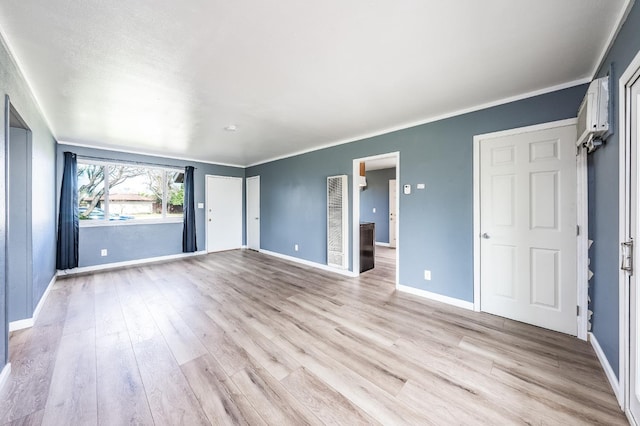 empty room featuring light wood-type flooring, baseboards, and crown molding