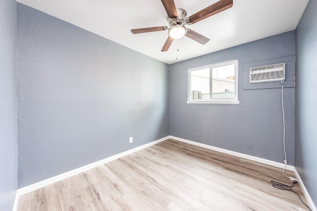 empty room featuring ceiling fan, baseboards, an AC wall unit, and wood finished floors