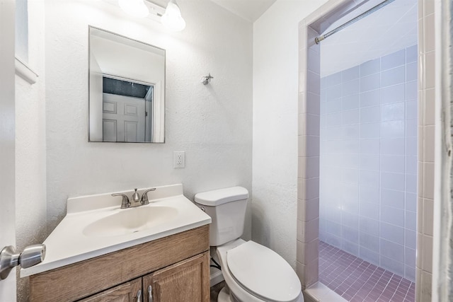 bathroom featuring vanity, a shower stall, toilet, and a textured wall