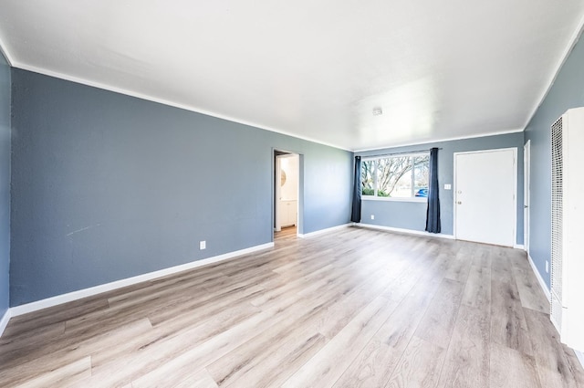 empty room with crown molding, baseboards, and wood finished floors