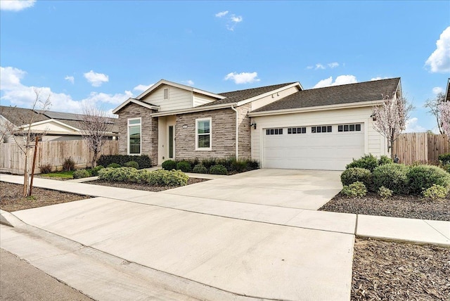 ranch-style home with stone siding, concrete driveway, an attached garage, and fence