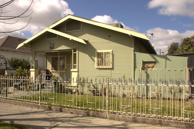 view of front facade with covered porch and a fenced front yard