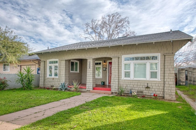 bungalow-style house featuring roof with shingles and a front lawn