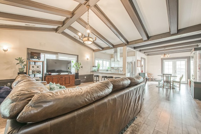 living area with vaulted ceiling with beams, light wood-style floors, a notable chandelier, and french doors