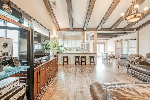 living room featuring beamed ceiling, light wood-type flooring, visible vents, and an inviting chandelier