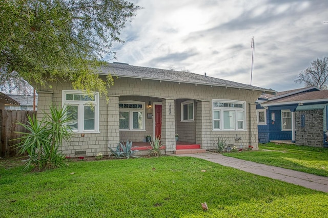 bungalow-style home featuring covered porch, fence, and a front lawn