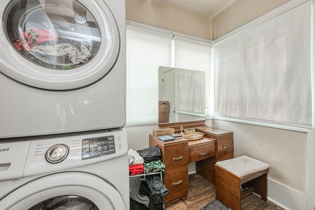 clothes washing area with stacked washing maching and dryer and wood finished floors