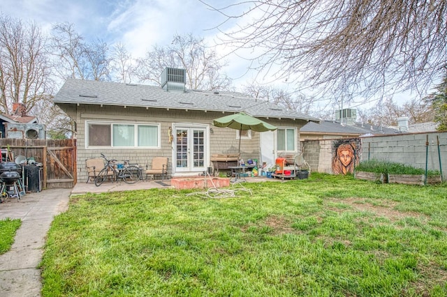 rear view of house featuring a patio, french doors, a lawn, and fence