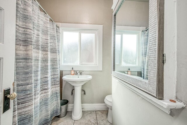 bathroom with tile patterned flooring, baseboards, toilet, and curtained shower