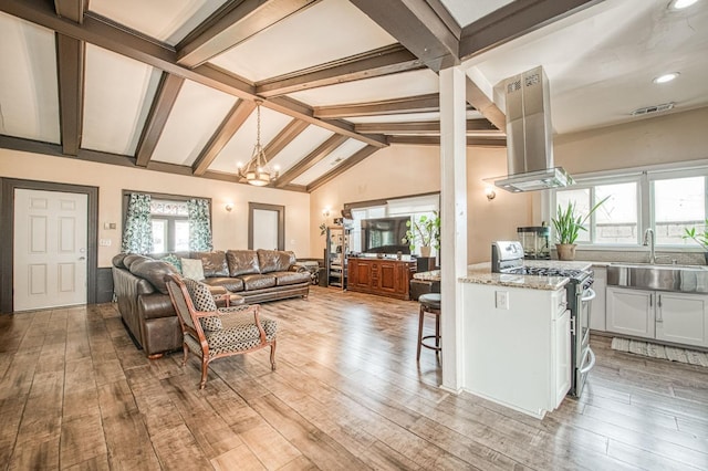 living room with light wood-style floors, a chandelier, visible vents, and lofted ceiling with beams