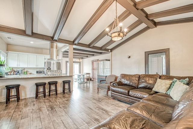 living area with lofted ceiling with beams, visible vents, light wood-style flooring, and a notable chandelier