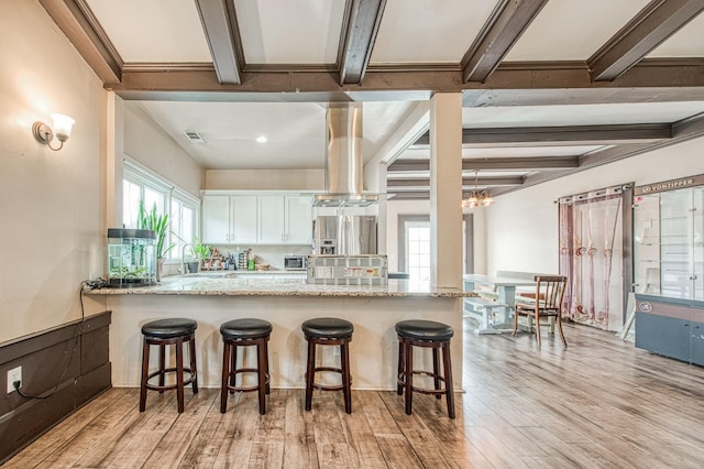 kitchen featuring a peninsula, white cabinetry, beam ceiling, and light wood-style floors