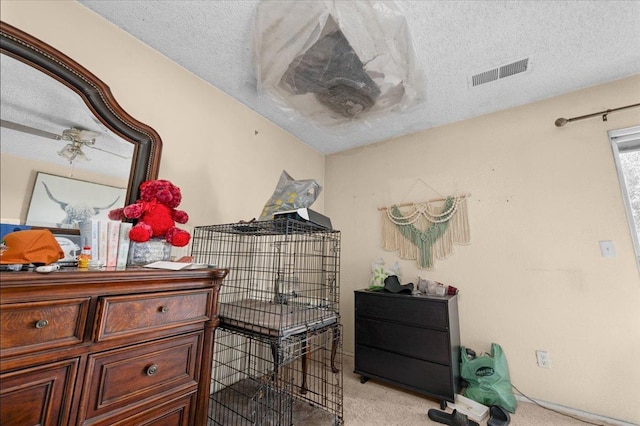 bedroom featuring light carpet, visible vents, and a textured ceiling