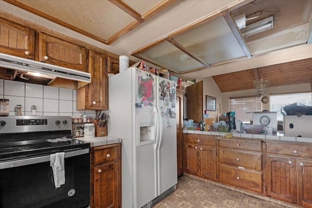 kitchen featuring white fridge with ice dispenser, brown cabinets, under cabinet range hood, and stainless steel electric stove