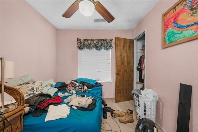 bedroom with carpet floors, a textured ceiling, visible vents, and a ceiling fan