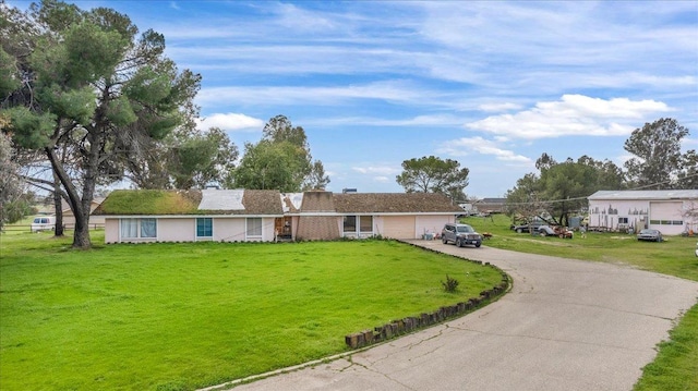 ranch-style home with a garage, driveway, and a front lawn