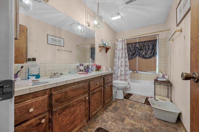 full bath with decorative backsplash, toilet, shower / tub combo, stone finish floor, and vanity