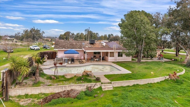 rear view of house with a fenced in pool, a patio area, a lawn, and stucco siding