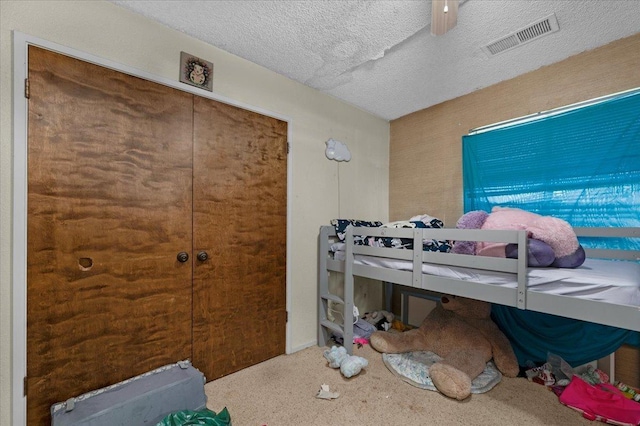 carpeted bedroom featuring a closet, visible vents, and a textured ceiling