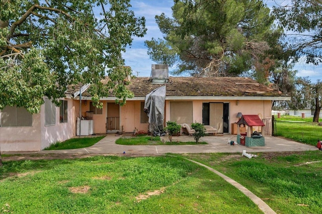 back of property with a chimney, a lawn, and stucco siding