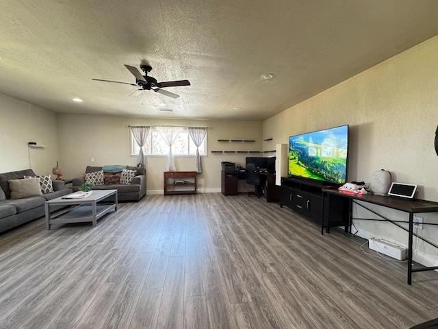 living area featuring ceiling fan, baseboards, wood finished floors, and a textured ceiling