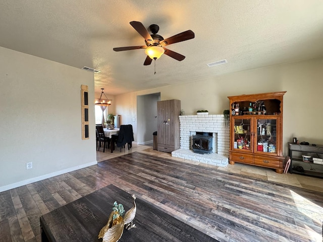 unfurnished living room with visible vents, ceiling fan with notable chandelier, a textured ceiling, and wood finished floors