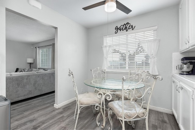 dining space featuring a ceiling fan, baseboards, and wood finished floors