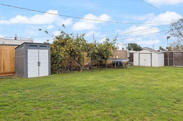 view of yard with a storage shed, a fenced backyard, a trampoline, and an outdoor structure