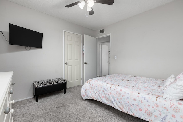 bedroom featuring visible vents, ceiling fan, light carpet, and a textured ceiling