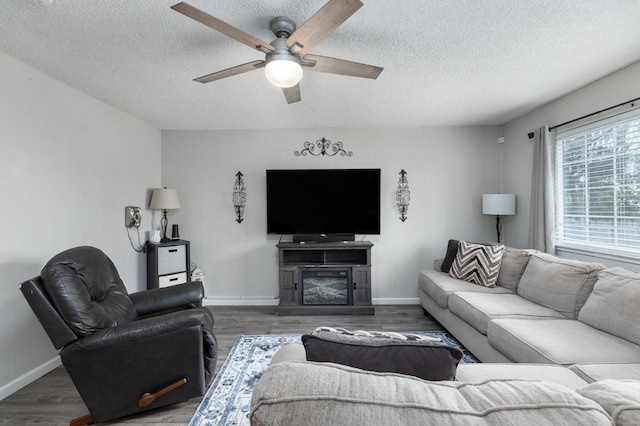 living area featuring ceiling fan, a textured ceiling, wood finished floors, and baseboards